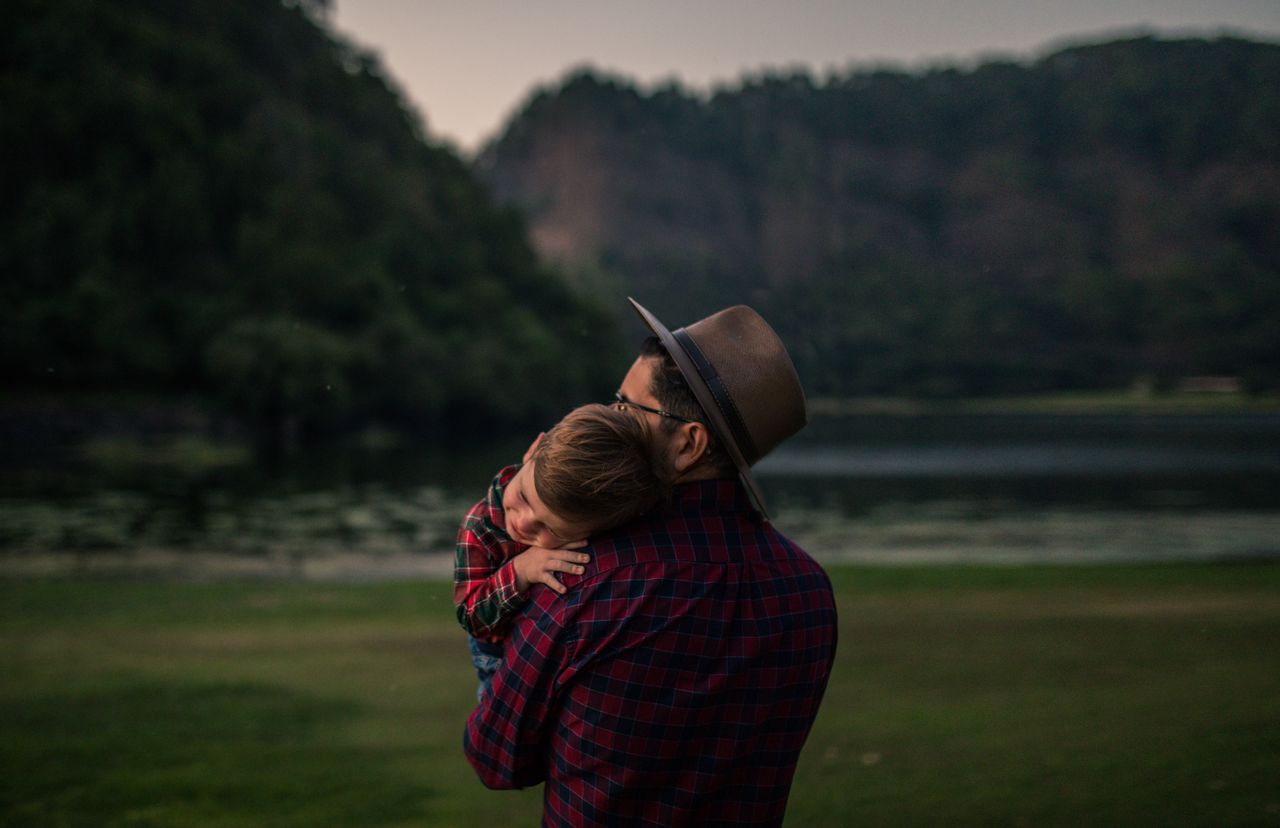 Un père tient son jeune fils dans ses bras au milieu de la nature