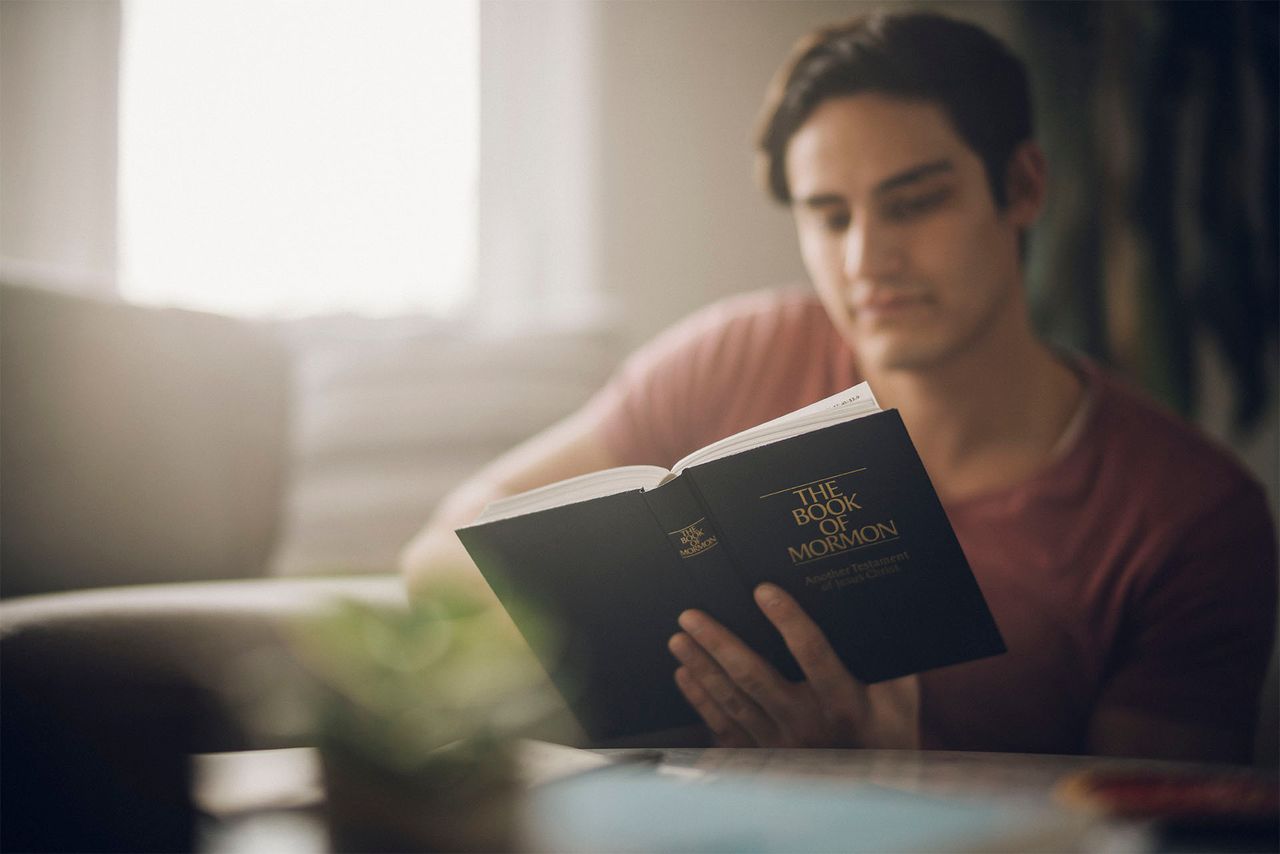 Un homme, assis à sa table de cuisine, étudie le Livre de Mormon