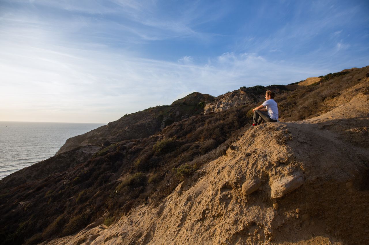 Une femme assise sur une falaise surplombant la mer réfléchit au pardon et au repentir